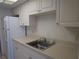 Compact kitchen featuring white cabinets, stainless steel sink, and full-size refrigerator at 1950 59Th N Ave # 212, St Petersburg, FL 33714