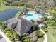 Aerial shot of community pool, patio furniture, tropical palm trees and adjacent pond at 35661 Jenny Lynne Cir, Zephyrhills, FL 33541