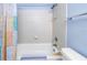 Clean white tiled tub and shower with a patterned shower curtain and blue accent wall at 3710 41St S Way # D, St Petersburg, FL 33711