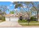 Attractive home with a three-car garage, complemented by mature trees and landscaping, creating a welcoming curb appeal at 4243 Tremblay Way, Palm Harbor, FL 34685