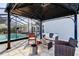 Relaxing covered patio with wicker seating, a gas fire pit, and views of the pool and garden at 4617 Cloverlawn Dr, Tampa, FL 33624