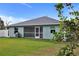 View of the backyard featuring green lawn, partial fence, and a house with a screened lanai and grill at 470 Sunset N Rd, Rotonda West, FL 33947
