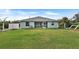 View of the backyard featuring green lawn, partial fence, and a house with a screened lanai at 470 Sunset N Rd, Rotonda West, FL 33947
