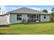 View of the backyard featuring green lawn, partial fence, and a house with a screened lanai and grill at 470 Sunset N Rd, Rotonda West, FL 33947