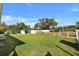 A spacious backyard is surrounded by a white fence and features lush green grass with stainless steel grill at 470 Sunset N Rd, Rotonda West, FL 33947