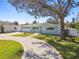 Charming single-story home boasts a large tree and a well-maintained lawn with a curved driveway at 5050 Venetian Ne Blvd, St Petersburg, FL 33703