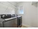 Modern laundry room with new washer and dryer units, window, and wire shelving at 520 Wheaton Trent Pl, Tampa, FL 33619