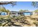 Backyard view of a pool with screen enclosure, shed, and blue house, surrounded by a lush green lawn and trees at 8248 Goodrich St, Spring Hill, FL 34606