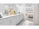 Bright bathroom featuring double sinks, white cabinetry, a walk-in shower, and an open doorway to a bedroom at 8435 Ocean Tides Cv, Parrish, FL 34219
