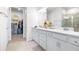 Bright bathroom featuring double sinks, white cabinetry, large mirror, walk-in shower, and large walk-in closet at 8435 Ocean Tides Cv, Parrish, FL 34219