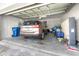 A spacious, well-lit garage with a modern car parked inside along with trash bins and storage at 8435 Ocean Tides Cv, Parrish, FL 34219