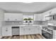Remodeled kitchen features stainless steel appliances, white subway tile, bright, white cabinets, and wood flooring at 8640 Tahoe Ct # 16, Tampa, FL 33614