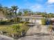 Charming single-story home with a well-manicured lawn, mature palm trees, and a driveway leading to an attached garage at 1015 55Th S Ave, St Petersburg, FL 33705