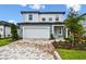 Charming two-story home showcasing a well-manicured lawn and a driveway paved with decorative brick at 10410 Cross River Trl, Parrish, FL 34219