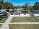 Aerial view of a single-story home with solar panels, surrounded by lush green lawns and a paved walkway at 11206 Mondale Ave, Seffner, FL 33584