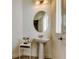 Powder room showcasing a pedestal sink, round mirror, and decorative accents next to the window at 11257 Egeria Dr, Odessa, FL 33556