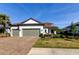 Charming home with a brick driveway, well-maintained lawn, mature palm trees and a three car garage at 11257 Egeria Dr, Odessa, FL 33556