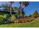 Beautiful community landscaping with vibrant flowers, mature trees, and green space under a clear blue sky at 11257 Egeria Dr, Odessa, FL 33556