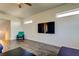 Bright living room featuring stylish gray wood flooring, a modern ceiling fan, and a flatscreen television at 11257 Egeria Dr, Odessa, FL 33556