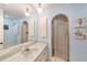 Light blue bathroom with tiled shower, large mirror, and elegant vanity at 139 Bluff View Dr # 105, Belleair Bluffs, FL 33770