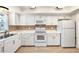 Bright kitchen featuring white cabinets, appliances, and decorative tile backsplash at 139 Bluff View Dr # 105, Belleair Bluffs, FL 33770