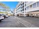 Exterior parking area for a complex of condos on a sunny day with spaces under the buildings at 139 Bluff View Dr # 105, Belleair Bluffs, FL 33770