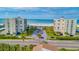 Aerial view of beachfront condos with manicured lawns and palm trees leading to the ocean at 1400 Gulf Blvd # 204, Clearwater Beach, FL 33767