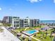 Breathtaking aerial view of a beachfront condo with a pool, tiki huts, manicured lawns, and ocean views at 1400 Gulf Blvd # 204, Clearwater Beach, FL 33767