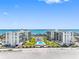 Expansive aerial view of beachfront condos with a pool and tiki huts offering stunning water views at 1400 Gulf Blvd # 204, Clearwater Beach, FL 33767