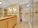 Well lit bathroom featuring a large mirror, wood cabinets and a tiled walk in shower at 1400 Gulf Blvd # 204, Clearwater Beach, FL 33767