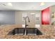 Close-up on kitchen sink with stainless steel faucet and granite countertop overlooking the living area at 18855 Hampstead Heath Ct, Land O Lakes, FL 34638