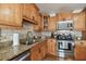Close up of kitchen features including granite counters, stainless steel appliances, tile backsplash, and wood cabinetry at 308 S Arrawana Ave, Tampa, FL 33609