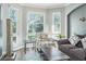 Living room with hardwood floors, a patterned chair, corner windows, and a comfortable sofa at 4037 Auston Way, Palm Harbor, FL 34685