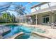 Screened-in pool and patio featuring a brick deck, spa, outdoor seating, and a heat lamp at 4037 Auston Way, Palm Harbor, FL 34685