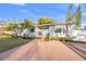 Charming single-story home featuring a brick driveway, manicured lawn, lush landscaping, and a welcoming light blue front door at 5 N Jupiter Ave, Clearwater, FL 33755