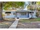 Charming front exterior showcasing a light blue home with a screened in porch and mature trees at 930 40Th Ne Ave, St Petersburg, FL 33703