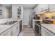 Well-lit galley kitchen features stainless steel appliances, granite countertops, and sleek white cabinets at 9481 Highland Oak Dr # 706, Tampa, FL 33647