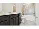 Bathroom with vanity, dark cabinets, sink, toilet and tub featuring neutral-toned tile work at 10537 Hidden Banks Gln, Parrish, FL 34219