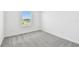 Bright bedroom featuring a window, white walls, and modern gray carpet at 10537 Hidden Banks Gln, Parrish, FL 34219
