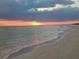 Calm waves gently washing onto the sandy shore with a vibrant sunset reflecting on the water at 113 Michigan Blvd, Dunedin, FL 34698