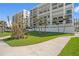 Lush lawn with palm trees, landscaping and walkway leading to the white beachfront condos at 1430 Gulf Blvd # 603, Clearwater Beach, FL 33767