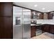 Modern kitchen featuring stainless steel appliances, dark wood cabinets, and a stylish backsplash at 1430 Gulf Blvd # 603, Clearwater Beach, FL 33767