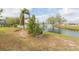 Landscaped backyard with a lake view, enhanced by tropical plants, brickwork, and mature trees at 1816 N Pebble Beach Blvd, Sun City Center, FL 33573