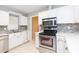 Well-lit kitchen featuring stainless steel appliances, mosaic backsplash, and white cabinets at 1816 N Pebble Beach Blvd, Sun City Center, FL 33573