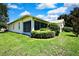 View of a white home with green grass and landscaping in the backyard, with a screened-in porch area at 18951 Grand Club Dr, Hudson, FL 34667