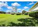Expansive green backyard with a side view of the home and lush landscaping at 18951 Grand Club Dr, Hudson, FL 34667
