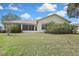 View of the home's backyard featuring lush landscaping and a screened-in lanai area at 18951 Grand Club Dr, Hudson, FL 34667