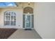 Inviting front entrance featuring an arched window, decorative glass door, and tiled walkway at 18951 Grand Club Dr, Hudson, FL 34667