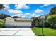 Charming front exterior featuring a three car garage and well manicured lawn at 18951 Grand Club Dr, Hudson, FL 34667