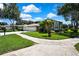 View of home's front yard, with a three-car garage and well-maintained landscaping on a sunny day at 18951 Grand Club Dr, Hudson, FL 34667